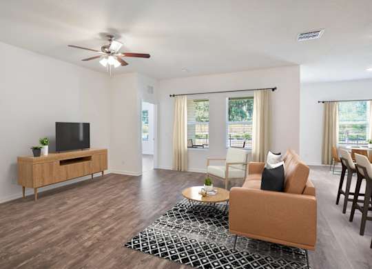 A living room with a brown sofa, a wooden entertainment center, and a ceiling fan.