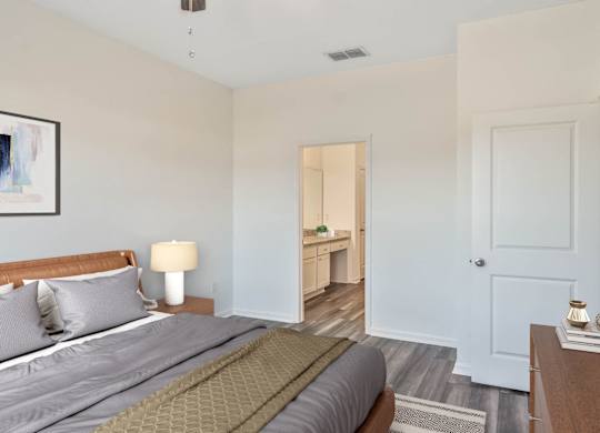 A bedroom with a bed, nightstand, and a painting on the wall.