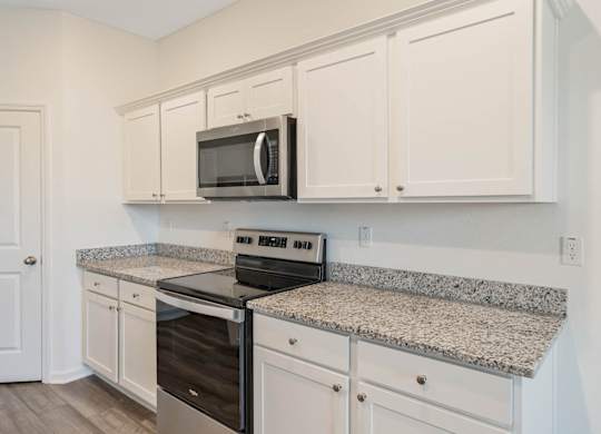 A kitchen with granite countertops and white cabinets.