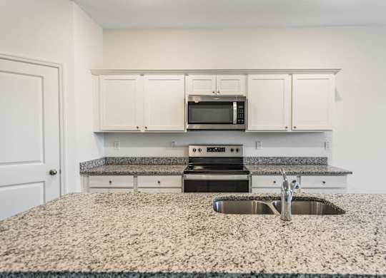 A kitchen with granite countertops and white cabinets.