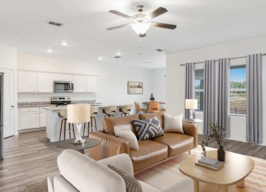 A modern living room with a brown leather couch and a white kitchen in the background.