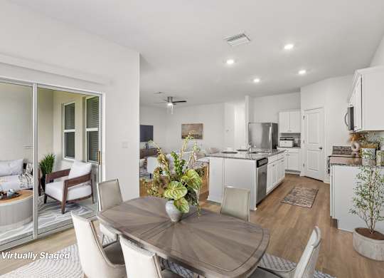 A modern kitchen with white cabinets and a dining table set for two.