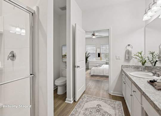 A bathroom with a glass shower door, a toilet, a sink, and a mirror.