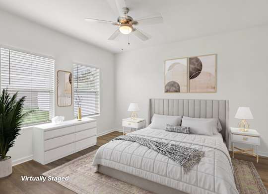 A bedroom with a large bed, a ceiling fan, and a potted plant.