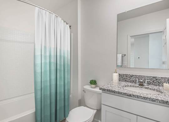 A white bathroom with a toilet, sink, and shower curtain.