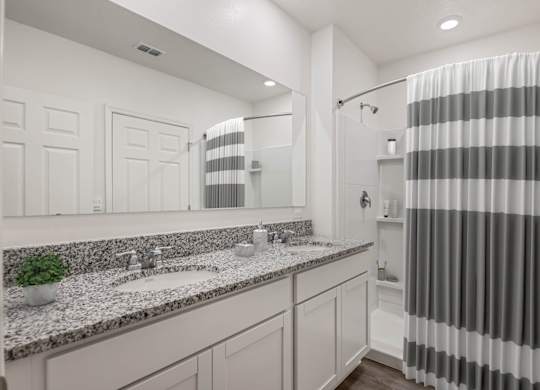 A bathroom with a striped shower curtain and a marble countertop.
