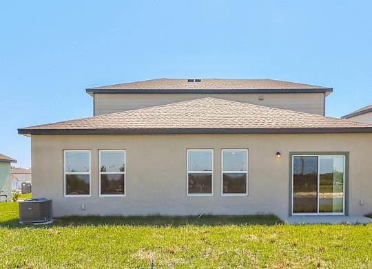 A house with a grey roof and beige walls with a window on the right side.