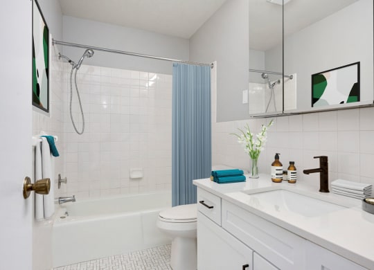 Laurel West End Apartments in Golden Valley, MN photo of a bathroom with white tiles and a blue shower curtain