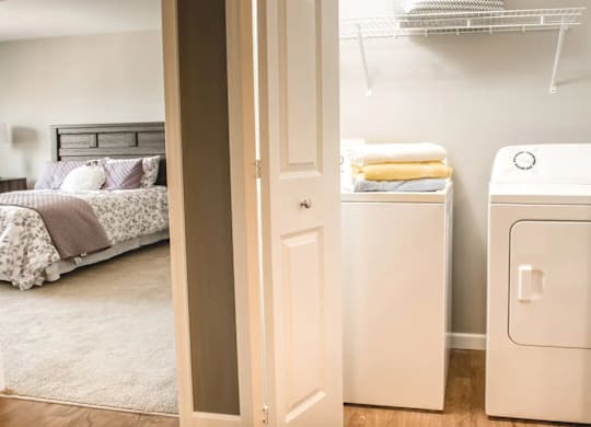 a bedroom with a washer and dryer and a closet with a bed