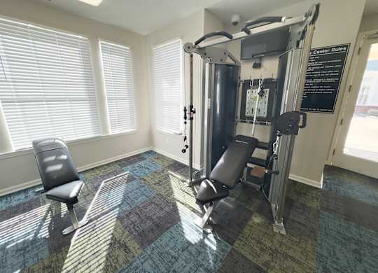 A gym room with a weight machine and a chair.
