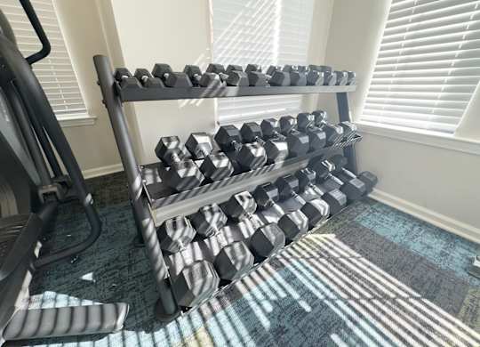 A rack of black dumbbells in a home gym.