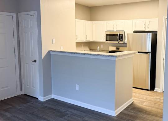 A kitchen with a white counter and a black fridge.