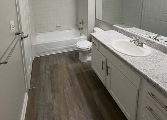 A bathroom with a white tub, toilet, and sink.