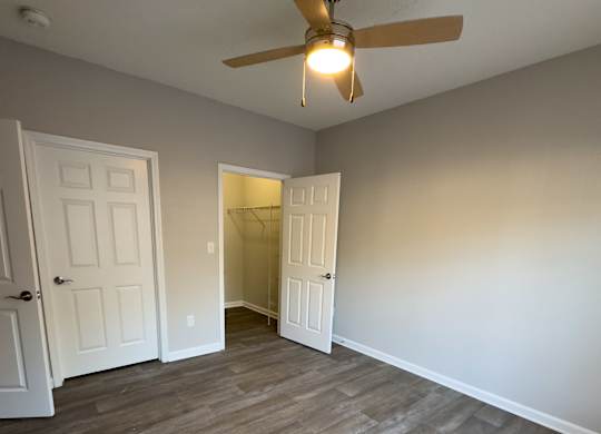 A room with a ceiling fan and wooden flooring.