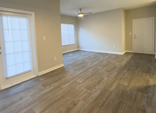 A room with light wood flooring and a ceiling fan.