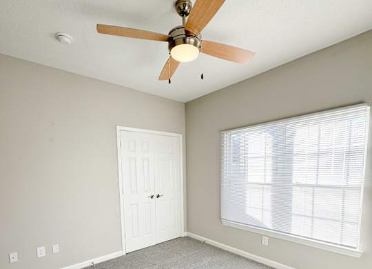 A room with a ceiling fan and a door.