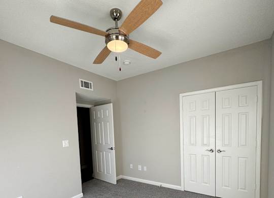 A room with a ceiling fan and carpeted floor.