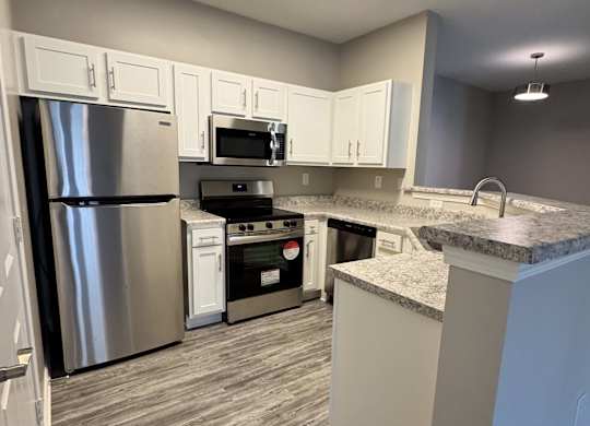A kitchen with a refrigerator, oven, and microwave.
