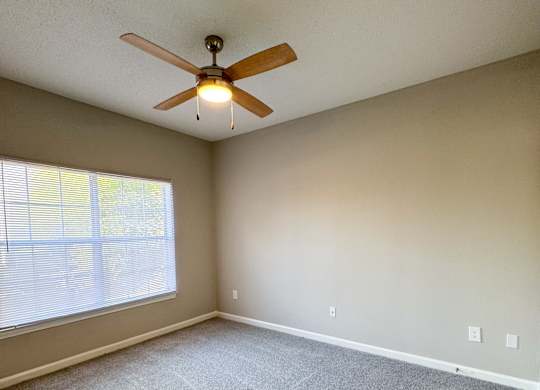 A room with a ceiling fan and carpeted floor.