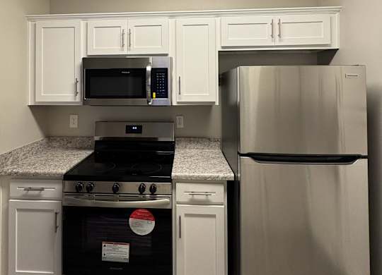 A kitchen with a stainless steel refrigerator and a black stove top oven.