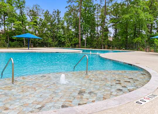 Homes for Rent with Attached Garage in Conroe, TX - Amber Pines at Foster's Ridge - Swimming Pool with Fountains, Umbrellas, Surrounded by Tall Trees