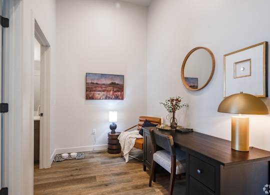 A room with a painting on the wall and a lamp on the desk.