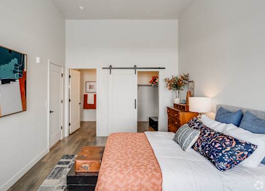 A bedroom with a bed, nightstand, and a painting on the wall.