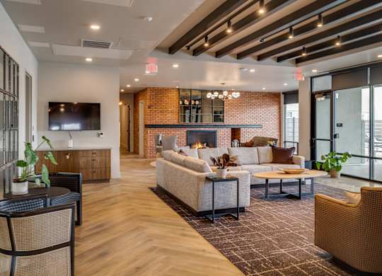 A modern living room with a brick wall and wooden floors.