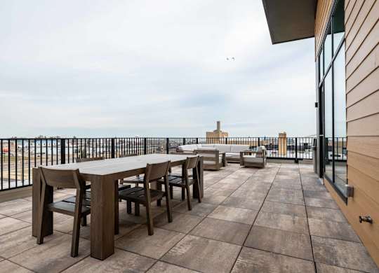A wooden table and chairs are set up on a wooden deck.