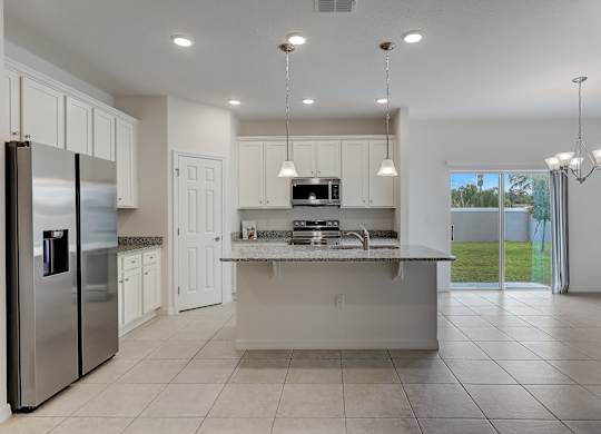 A modern kitchen with a refrigerator, sink, and cabinets.
