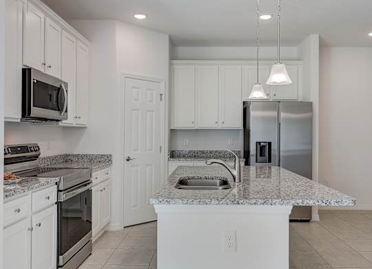 A kitchen with white cabinets and a marble countertop.