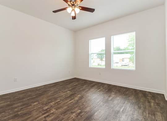 A room with a ceiling fan and wood flooring.