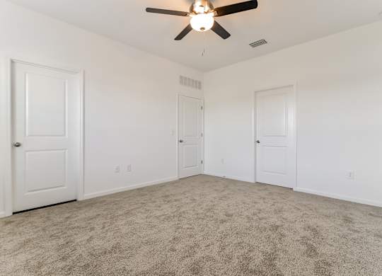 A room with a ceiling fan and carpeted floor.