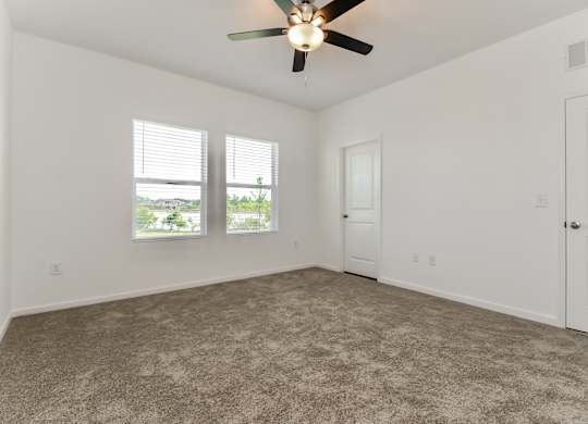 A room with a ceiling fan and carpeted floor.