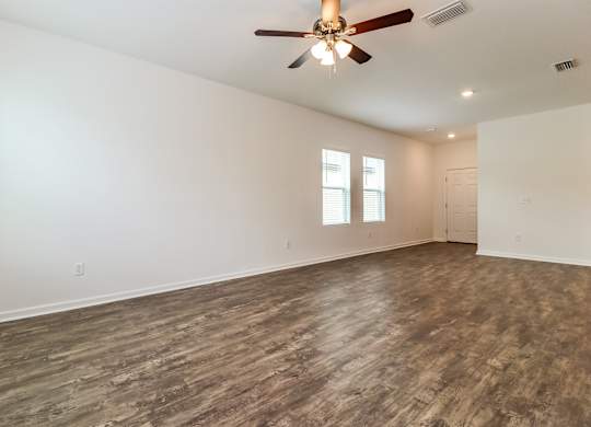 A room with a ceiling fan and wood flooring.