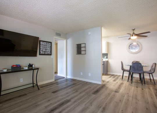 Tucson, AZ, Apartments - Peaks at Redington - Open Floor Plan Living Room with Wood-Style Flooring, TV, and View of Dining Area and Kitchen.