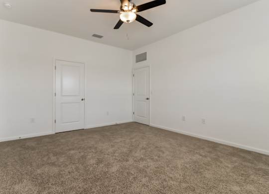 A room with a ceiling fan and carpeted floor.