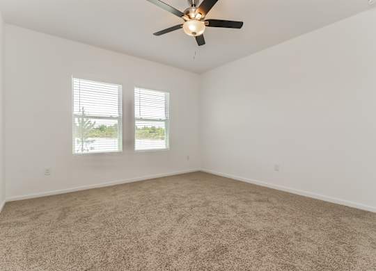 A room with a ceiling fan and carpeted floor.