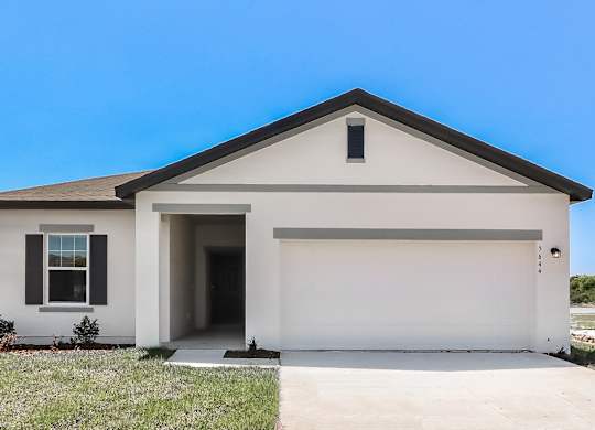 A white house with a black roof and a garage door.