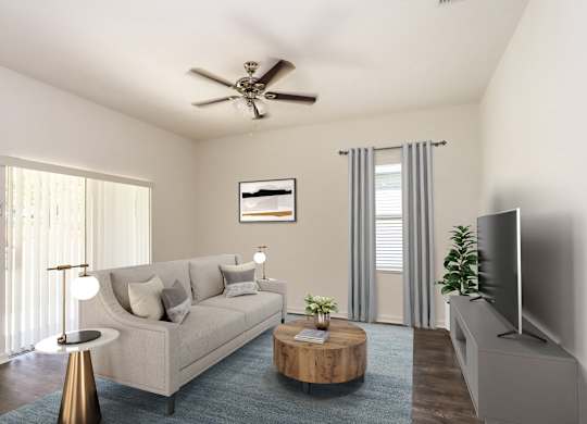 A living room with a beige couch, a coffee table, a television, and a ceiling fan.
