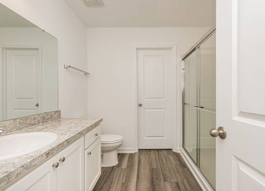 A white bathroom with a sink, toilet and a door.