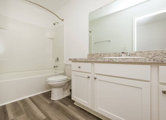 A white toilet sits in a bathroom next to a bathtub.