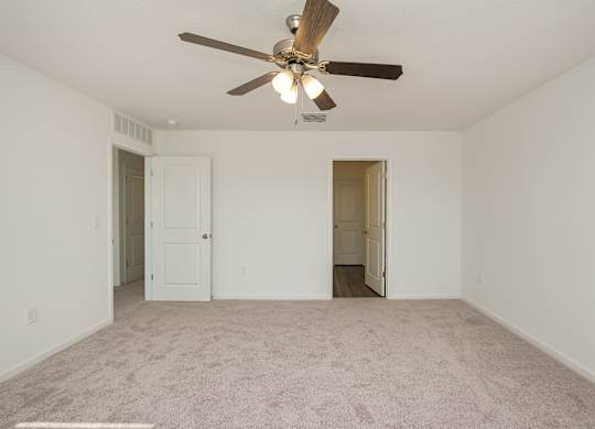 A room with a ceiling fan and carpeted floor.
