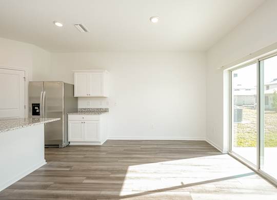 A kitchen with white cabinets and a refrigerator.