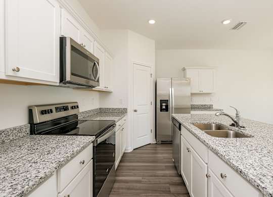 A kitchen with granite countertops and white cabinets.