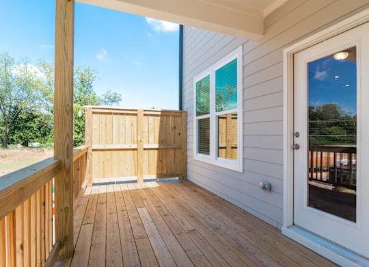 A wooden deck with a white door and a window.
