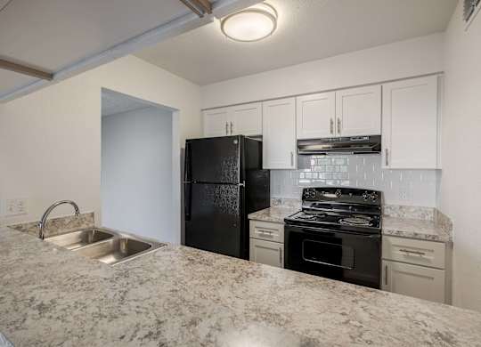 A kitchen with granite countertops and white cabinets.