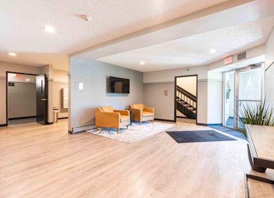 A spacious room with a staircase, a television, and a couple of chairs.