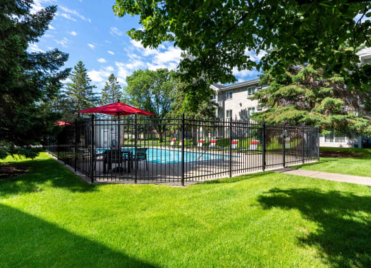 a fenced in pool with a table and umbrella in a yard