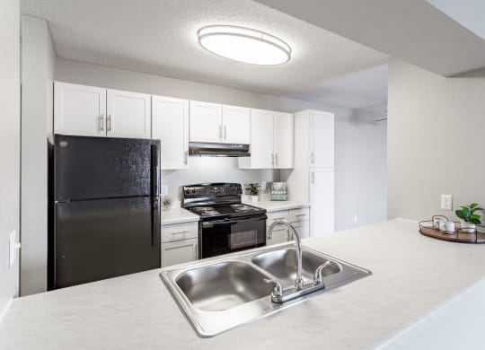 a kitchen with white cabinets and black appliances